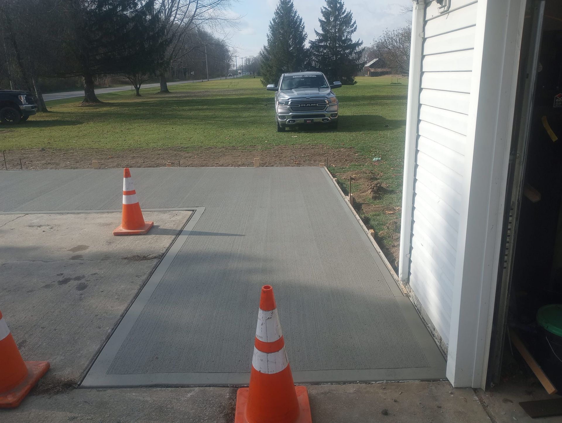 A car is parked in a driveway next to traffic cones.