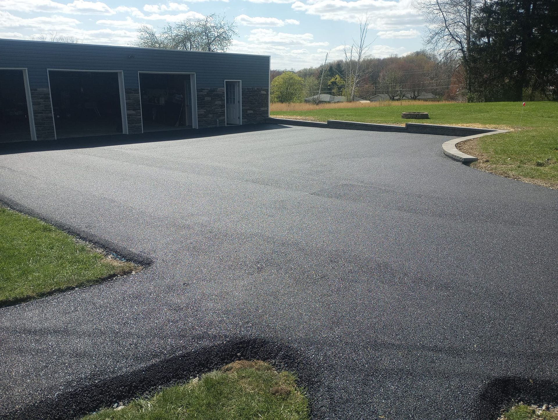 A driveway with a garage in the background and a grassy area in the foreground.