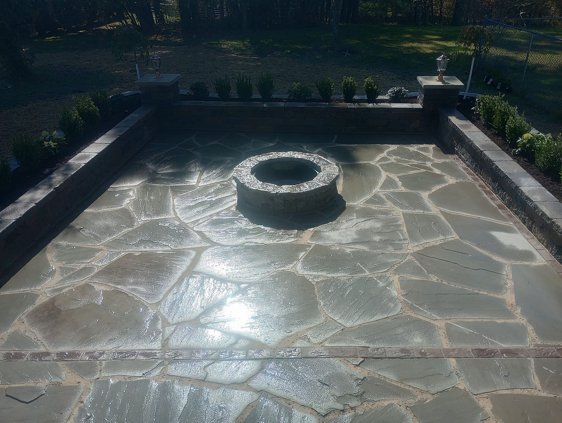 A stone patio with a fire pit in the middle