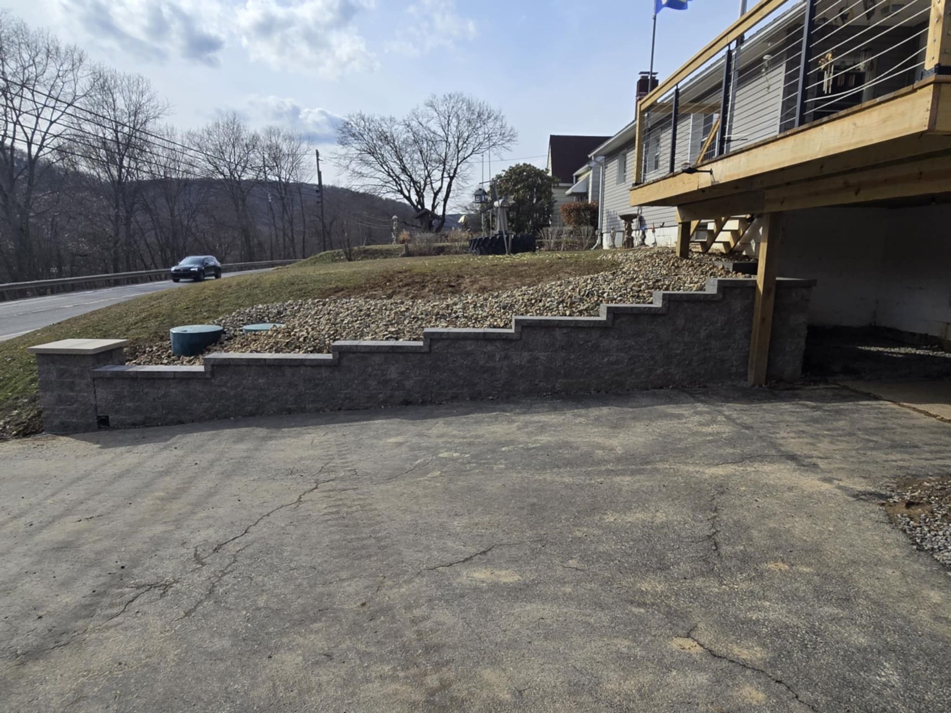 A concrete wall with stairs leading up to a house with a deck.