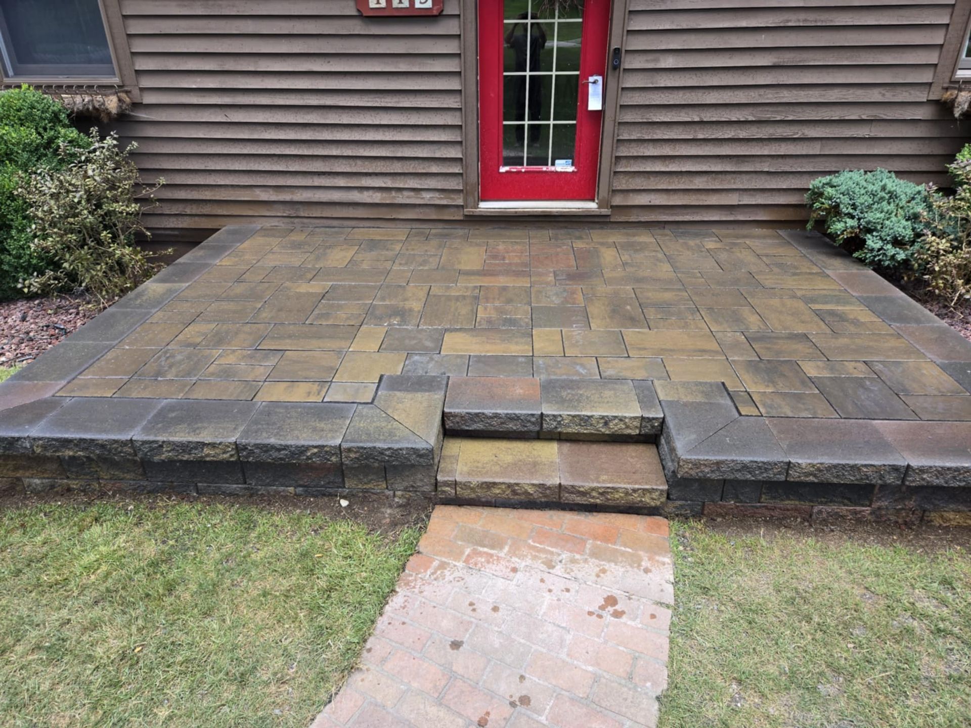 A brick walkway leads to the front door of a house