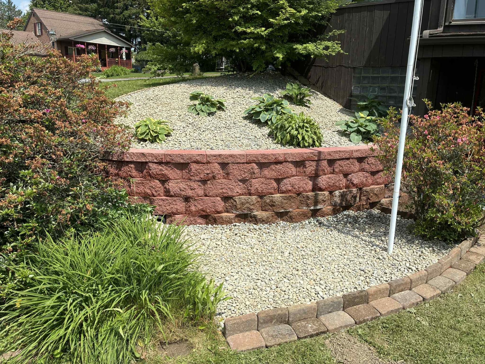 A brick wall is surrounded by gravel and plants in a garden.