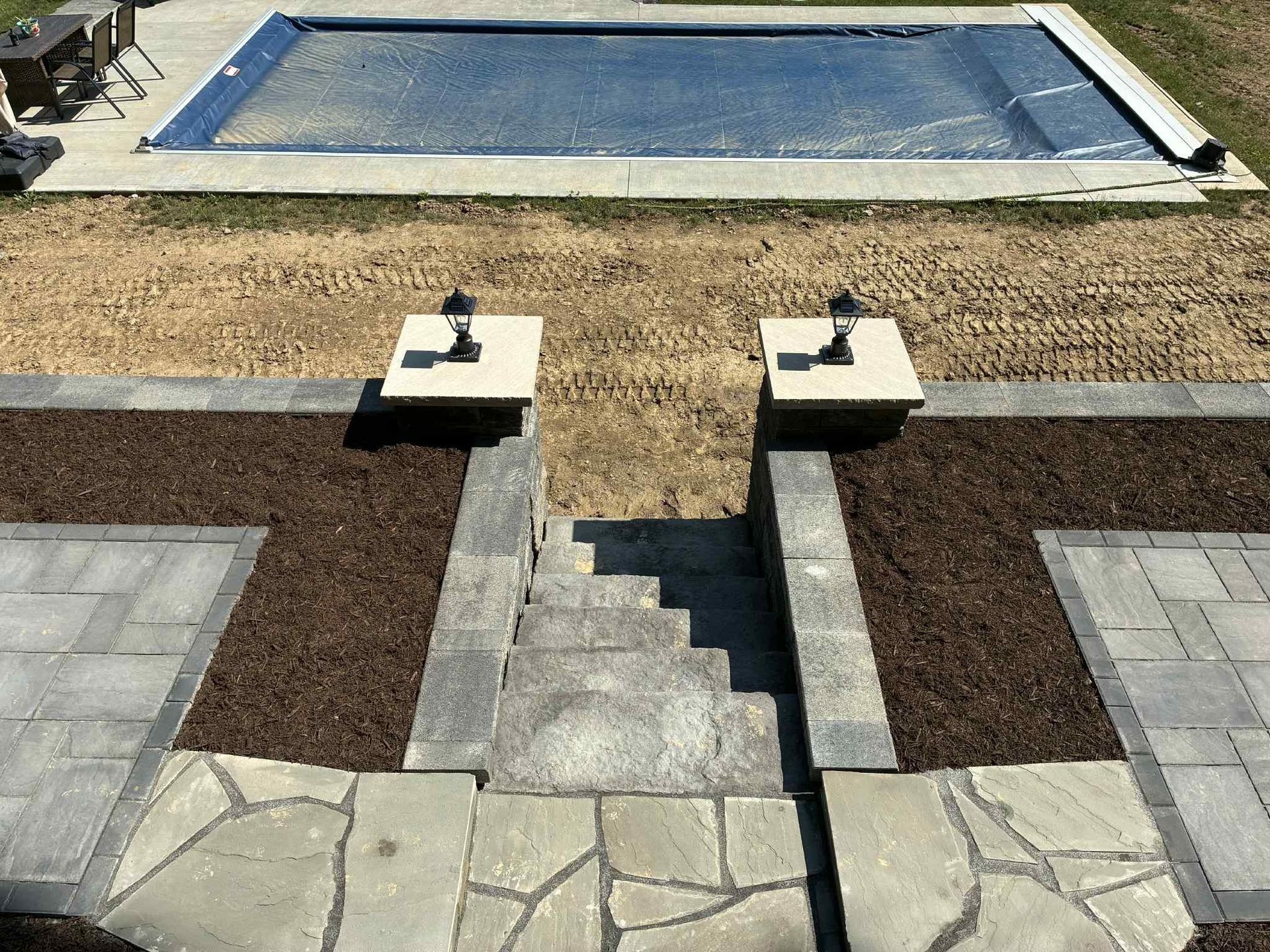 A large swimming pool is surrounded by a stone walkway and stairs.