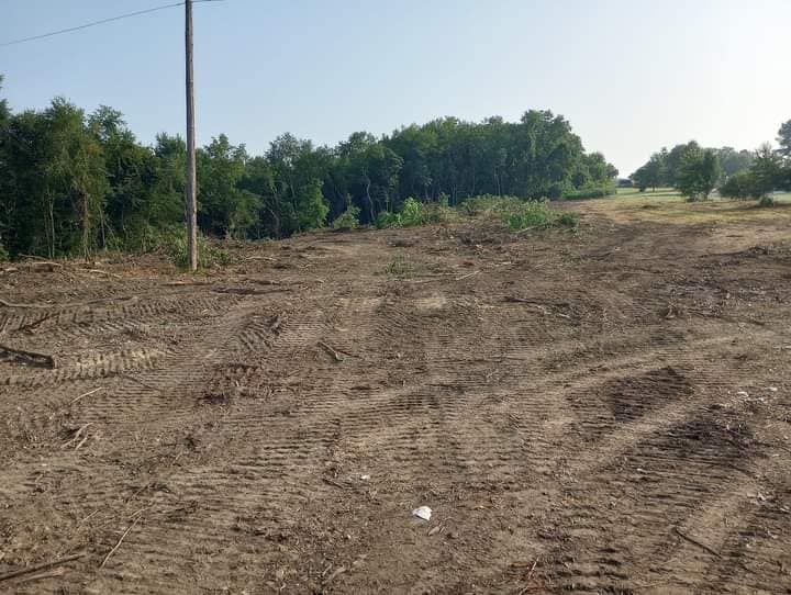 A large dirt field with trees in the background