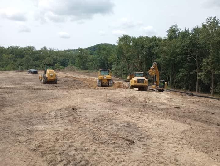 A group of construction vehicles are working on a dirt road.