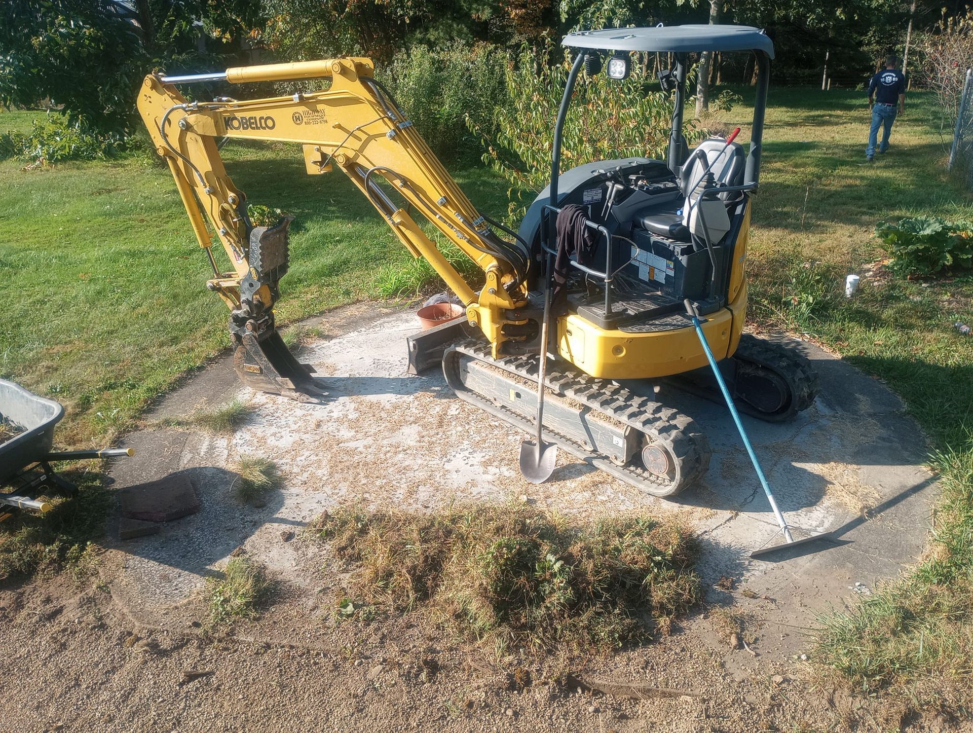 A small yellow excavator is sitting in the middle of a yard.