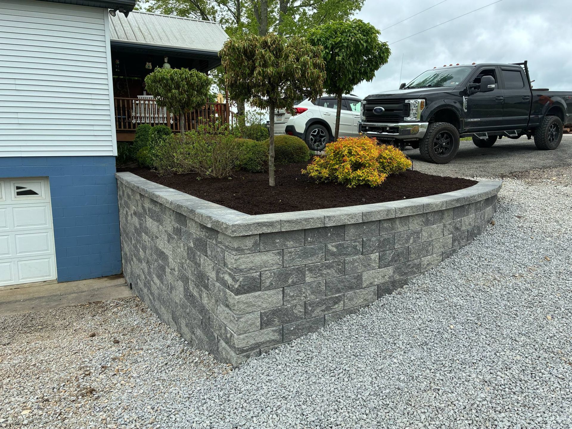 A truck is parked in front of a house next to a brick wall.