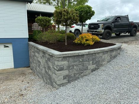 A truck is parked in front of a house next to a brick wall.