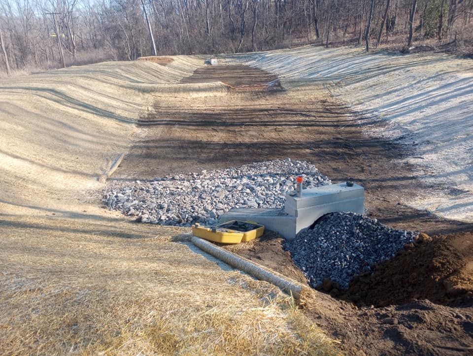 A large pile of rocks is sitting in the middle of a dirt field.