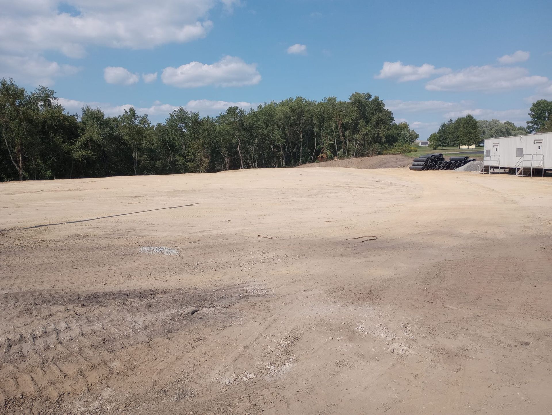 A large dirt field with trees in the background