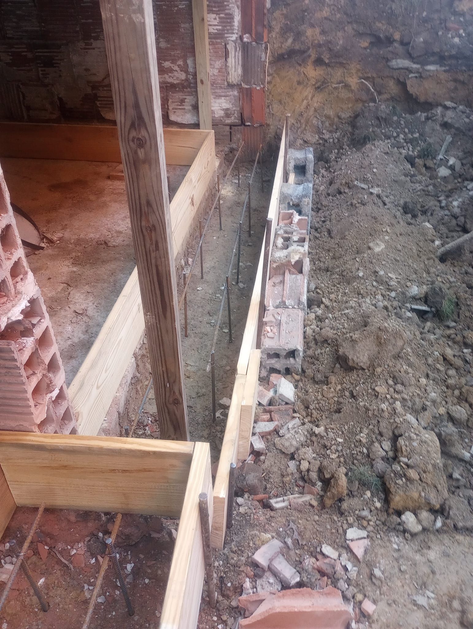 A brick wall is being built in a hole in the ground.