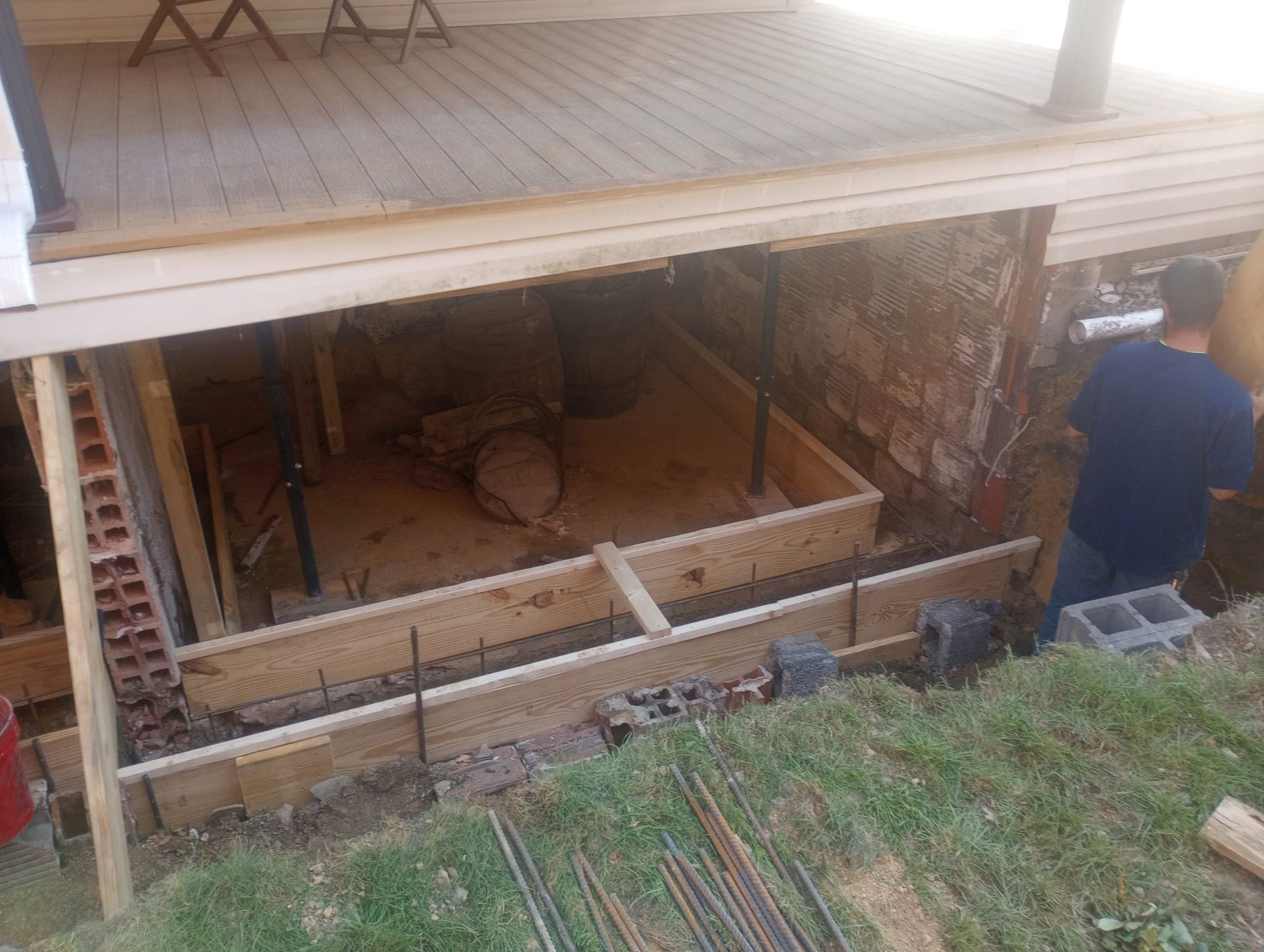 A man is working on a basement under a deck.