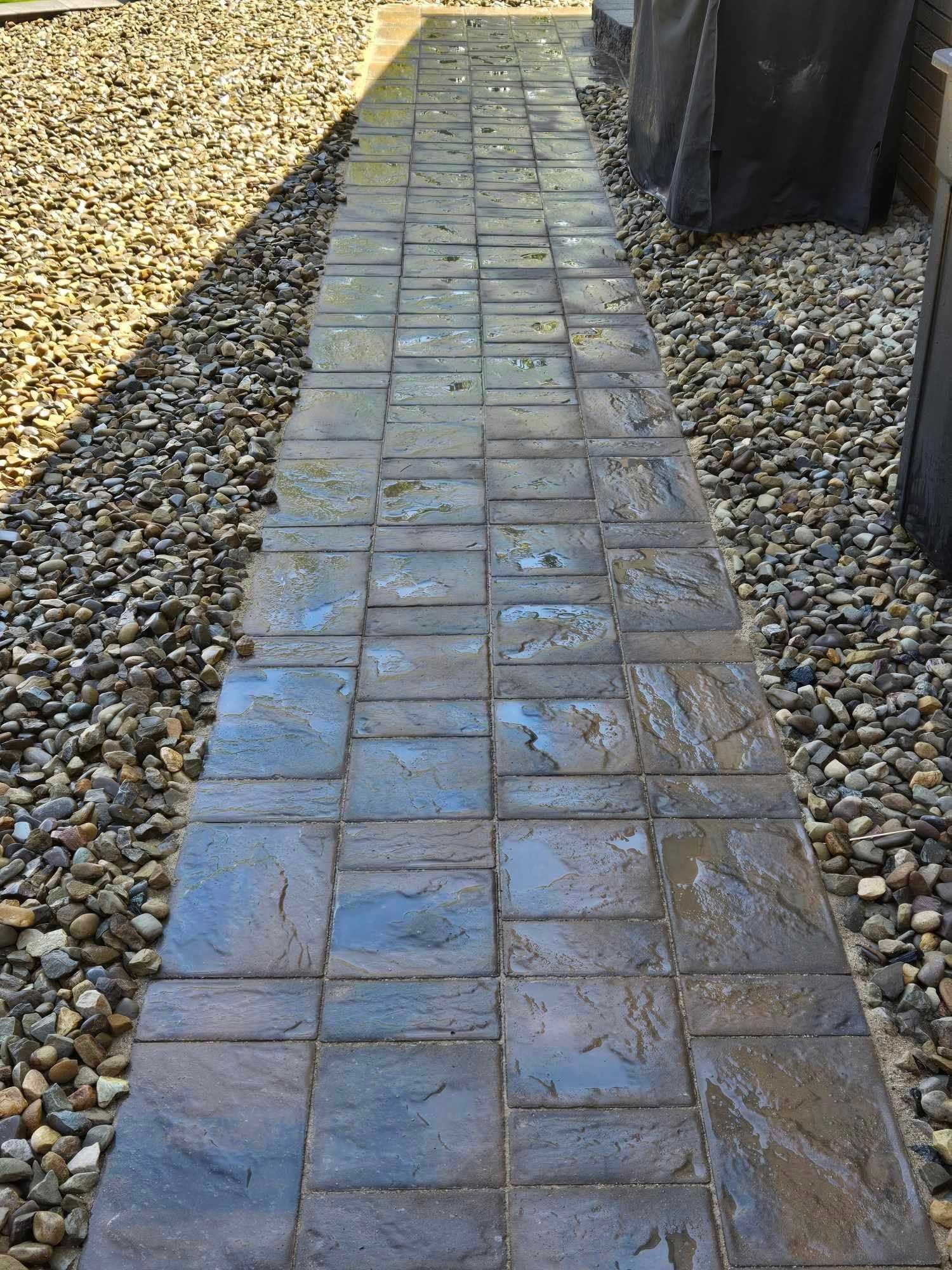 A brick walkway leading to a gravel area.