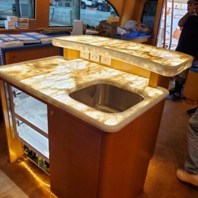 A man is taking a picture of a kitchen counter with a sink