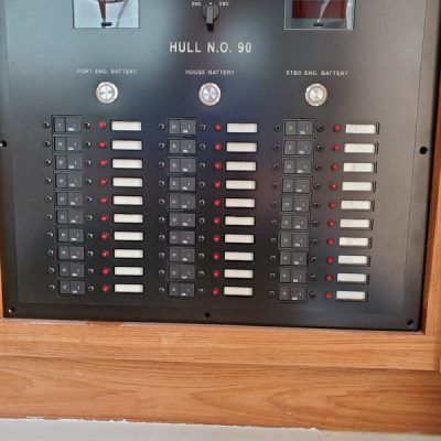 A control panel with a lot of buttons on it is sitting on a wooden wall.