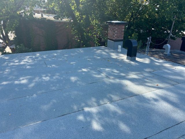 Un toit avec une cheminée dessus et des arbres en arrière-plan