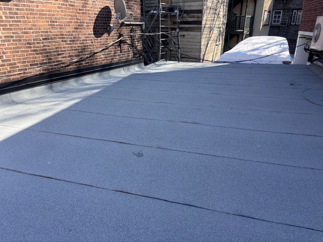 Un toit avec une antenne parabolique dessus et un bâtiment en briques en arrière-plan.