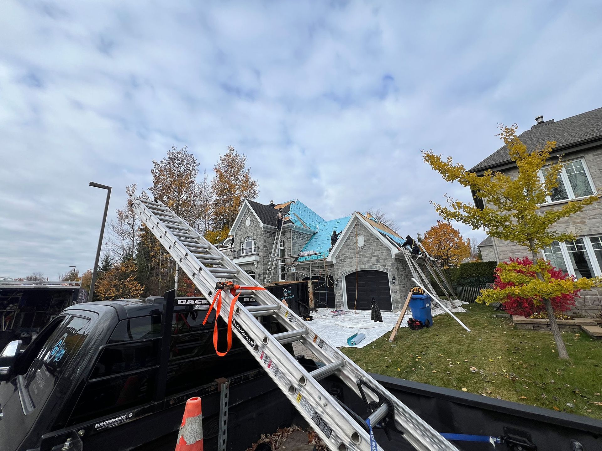 Une échelle est posée à l'arrière d'un camion devant une maison.