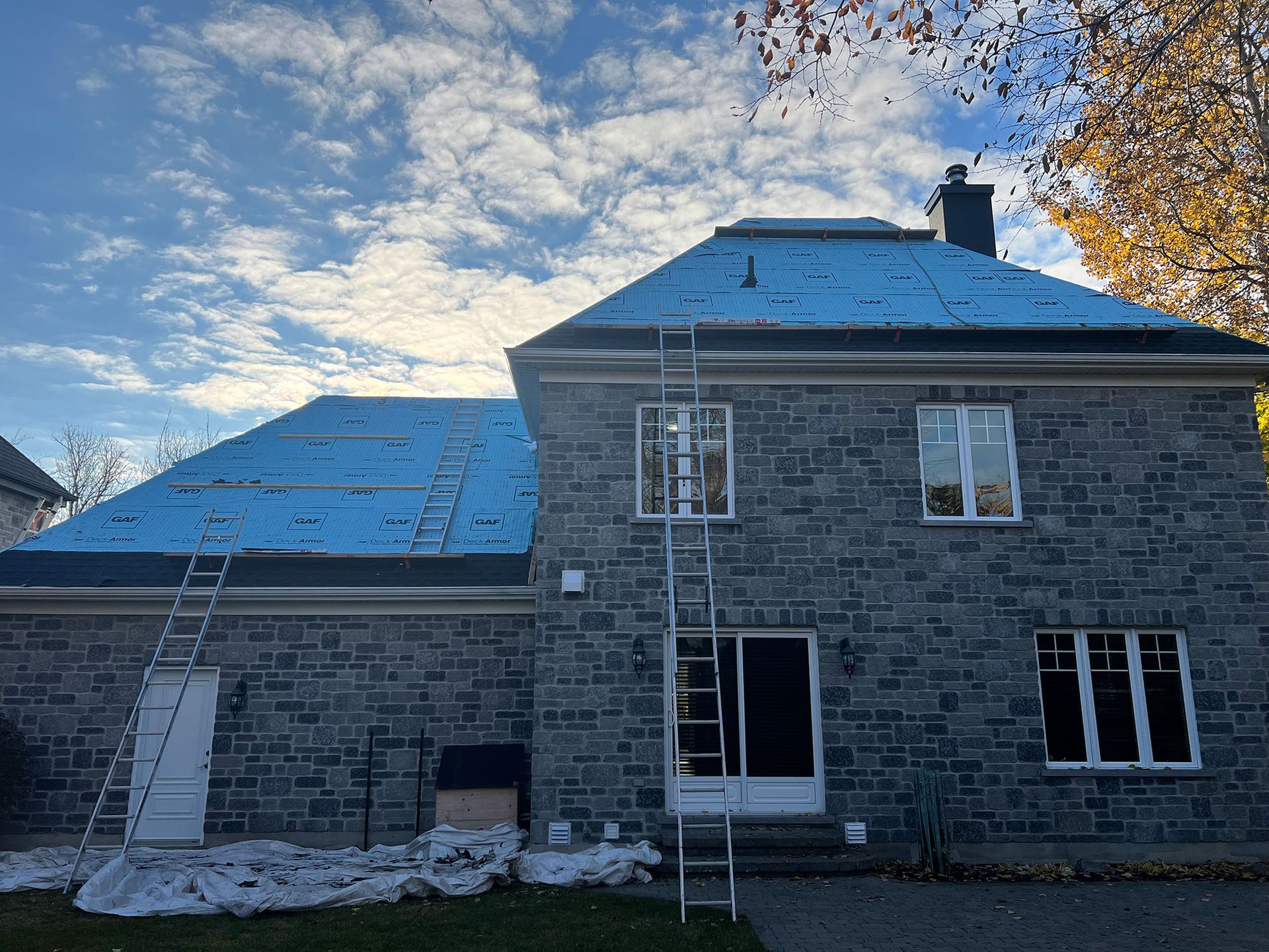 Une maison en briques avec un toit bleu et une échelle devant.