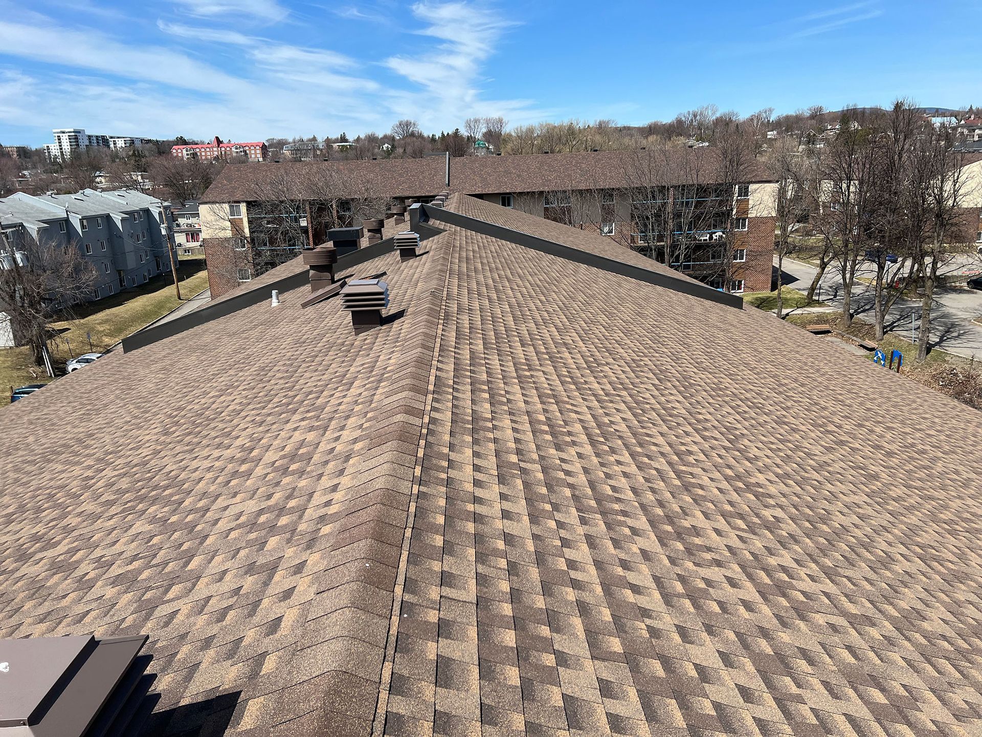 Le toit d'une maison avec un toit marron et un ciel bleu en arrière-plan.