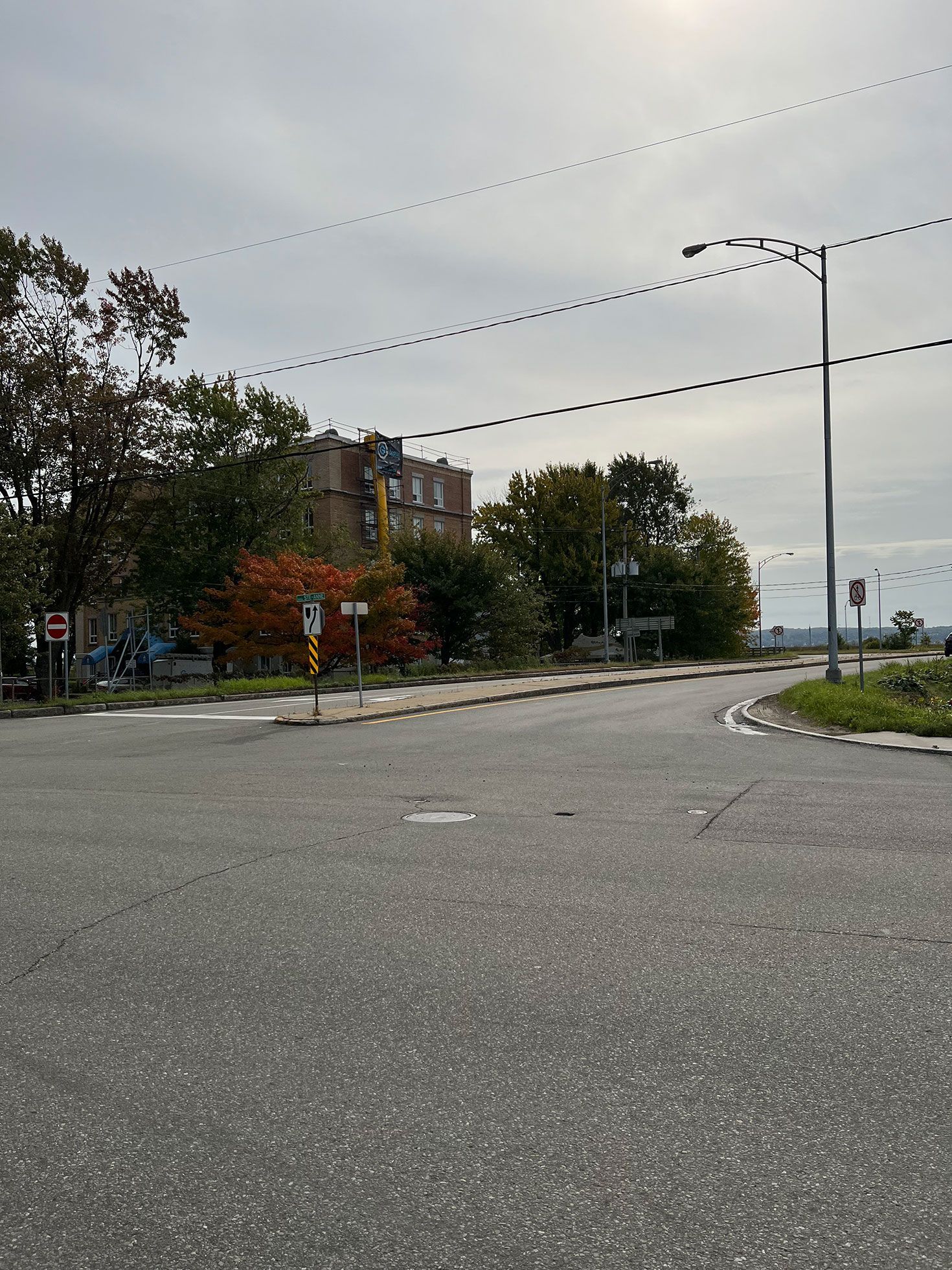 Une intersection vide avec un bâtiment en arrière-plan et des arbres sur le côté de la route.