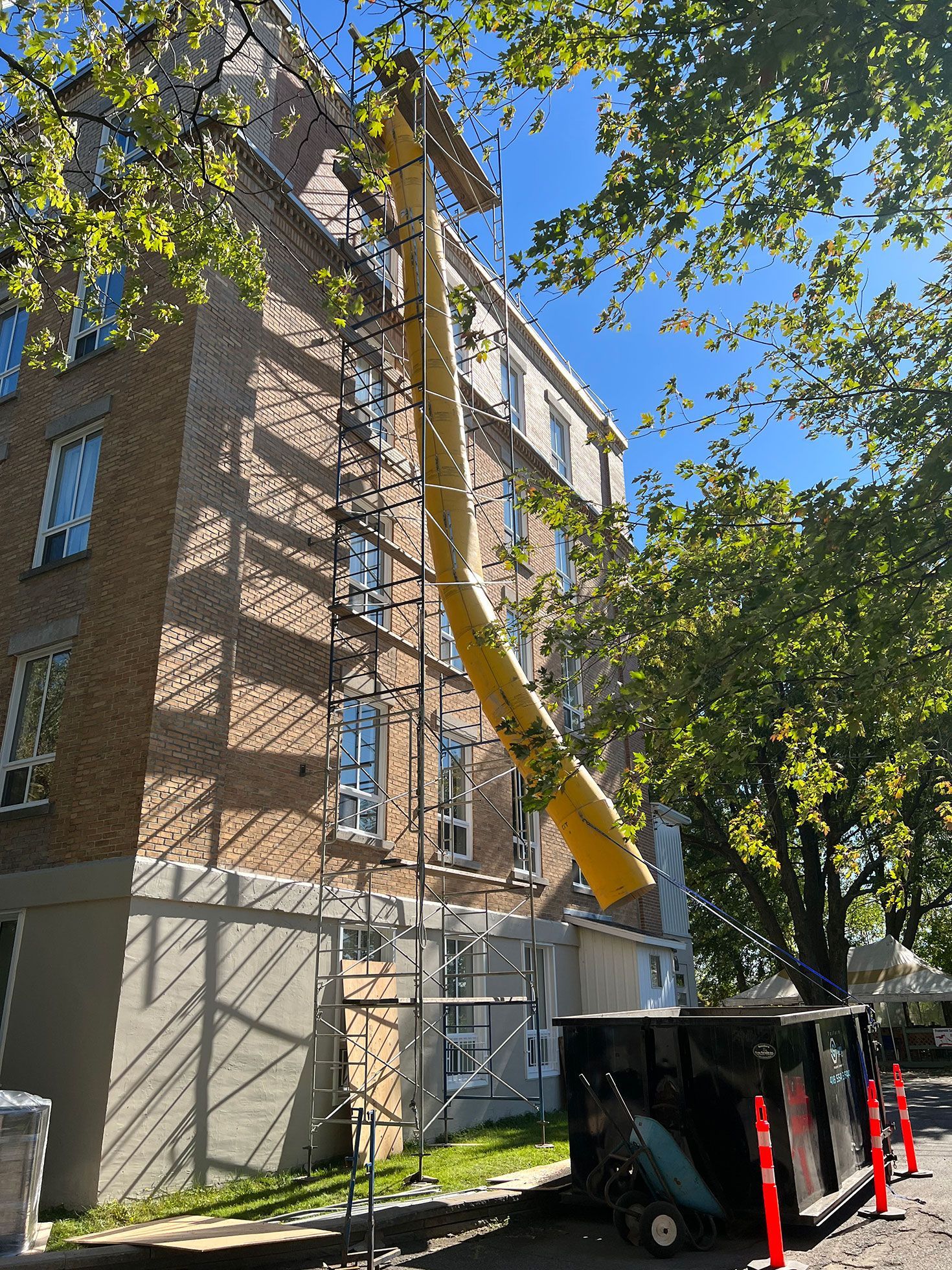 Un gros tuyau jaune est utilisé pour retirer le toit d'un bâtiment.