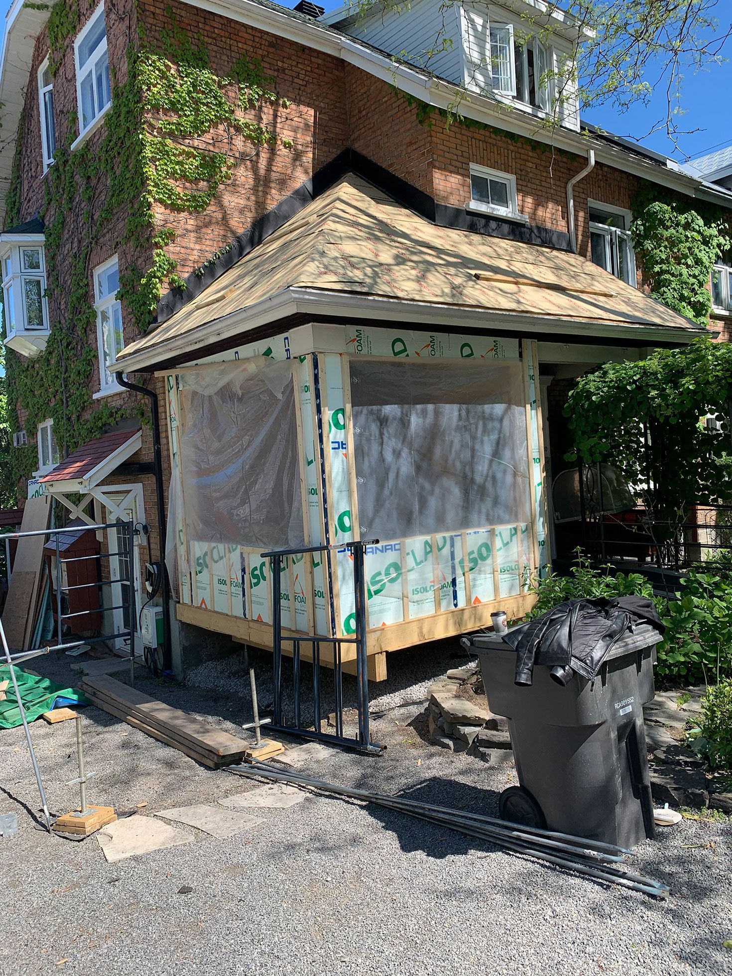 Un petit bâtiment est en construction devant une maison en briques.