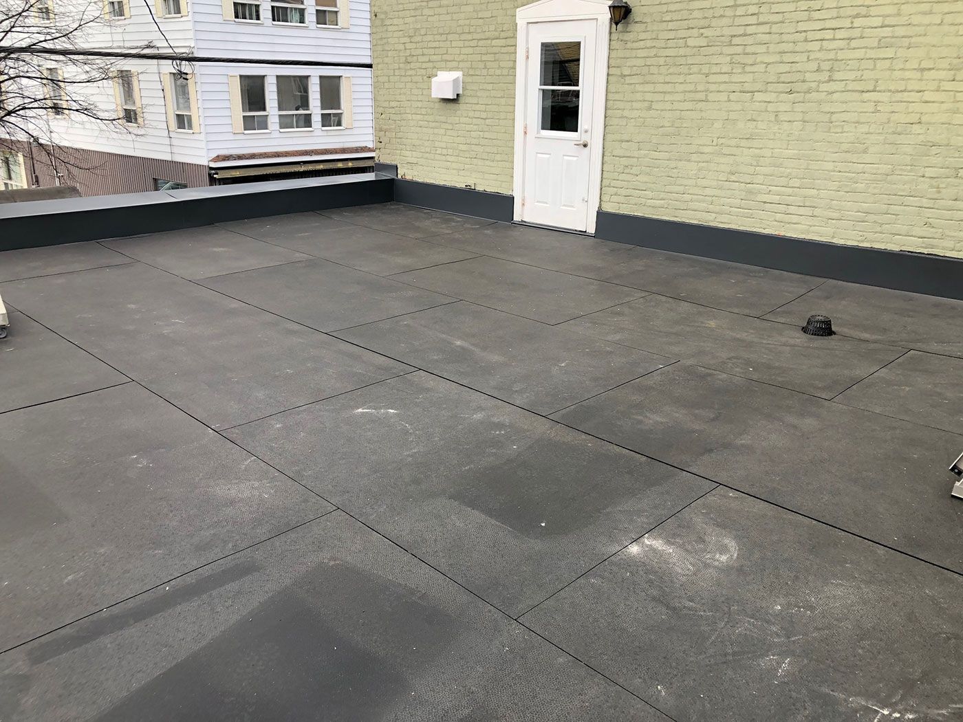 Un toit avec une porte en arrière-plan et un bâtiment en briques en arrière-plan.