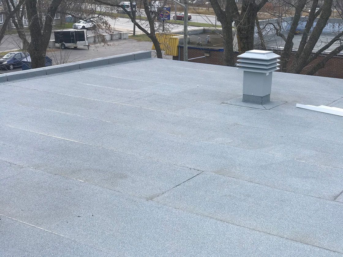 Un toit avec une cheminée dessus et des arbres en arrière-plan.