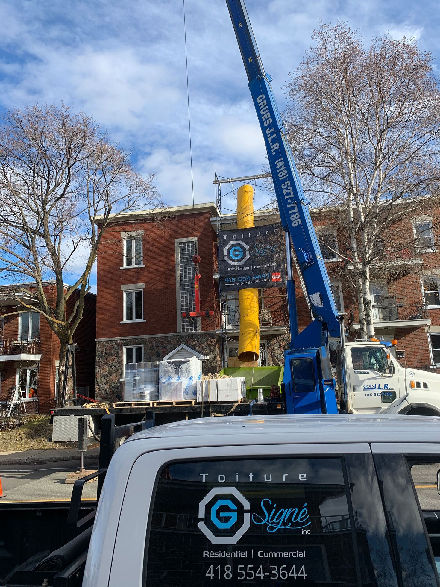 Un camion avec une grue dessus est garé devant un bâtiment.