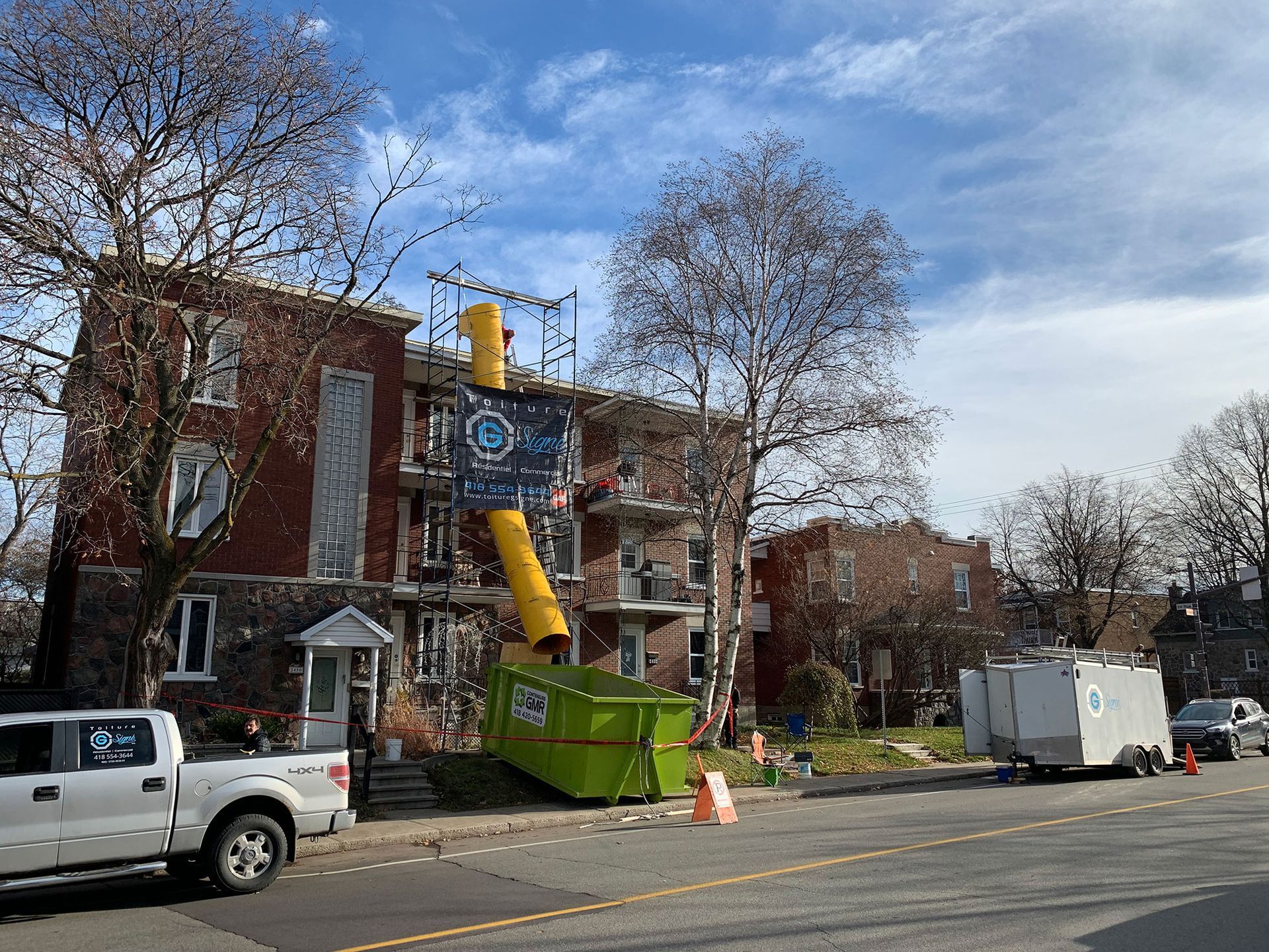 Un camion blanc est garé sur le bord de la route devant un bâtiment en construction.