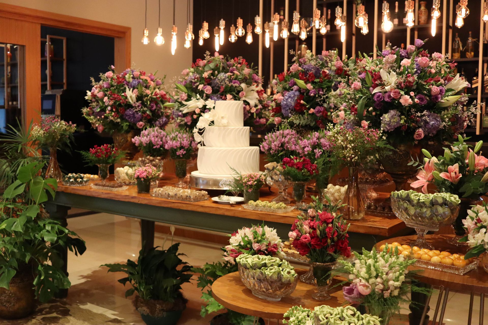 Uma mesa está decorada com muitas flores e um bolo.