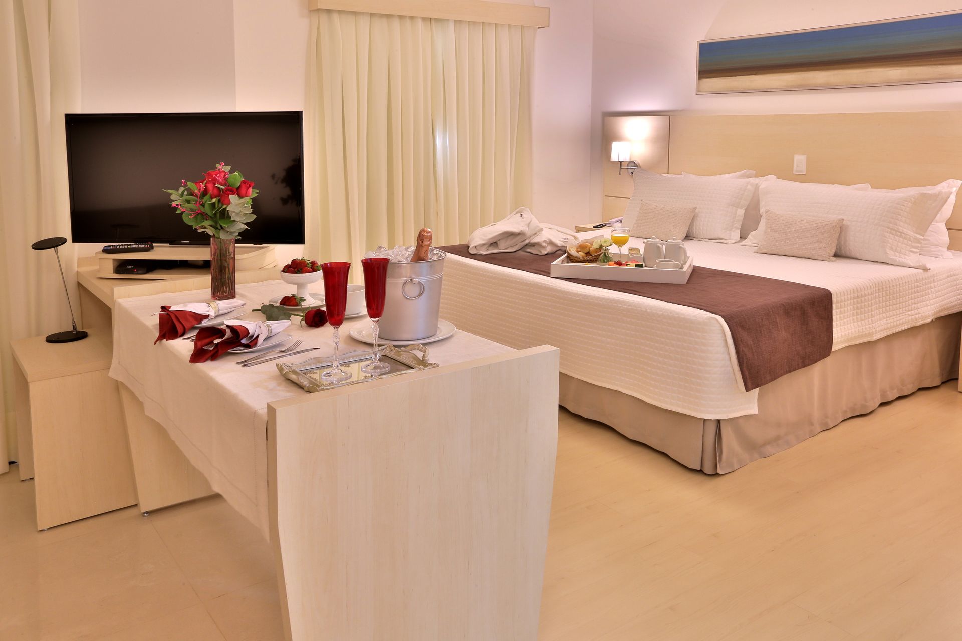 Um quarto de hotel com duas camas, uma mesa e uma televisão.