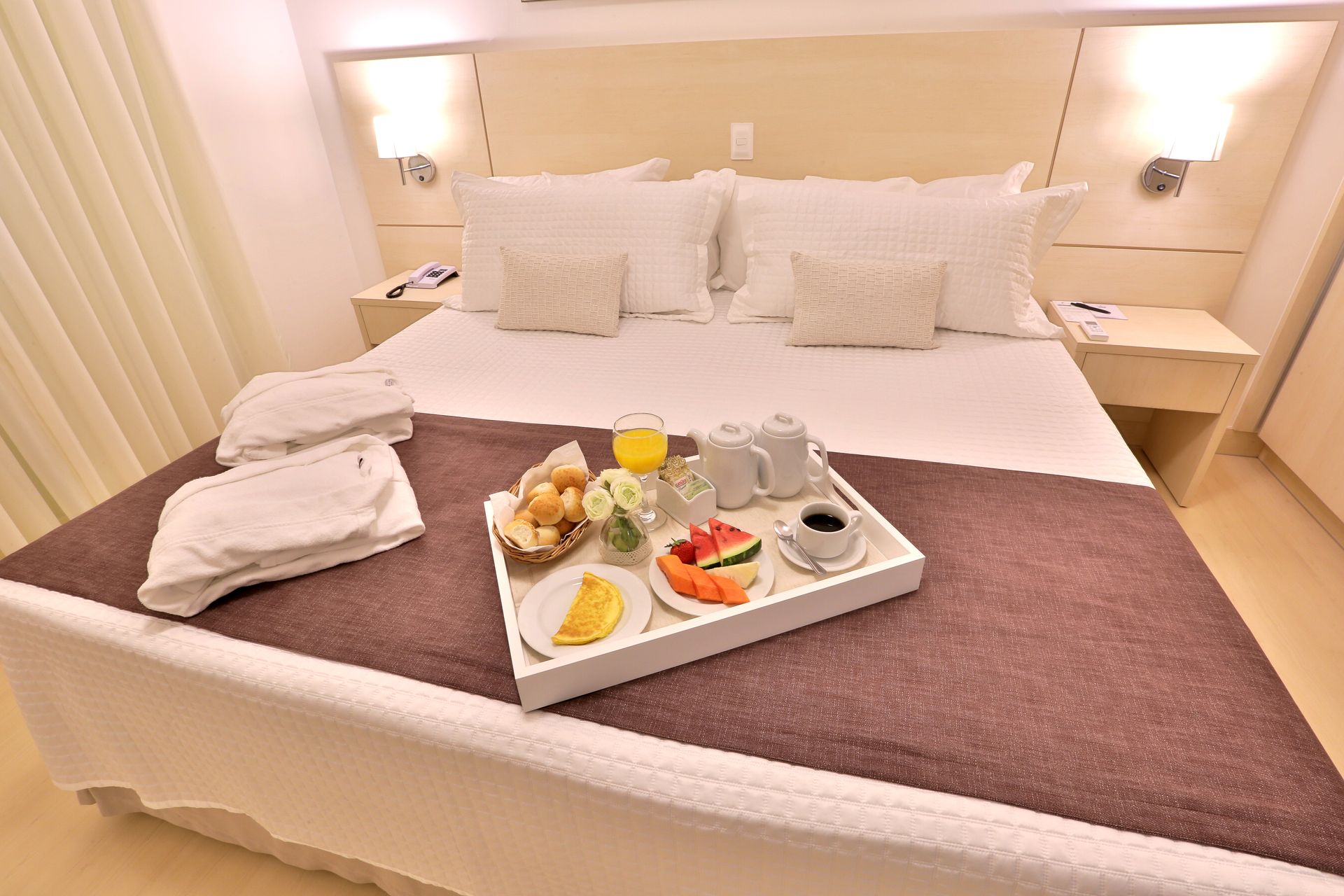 Um quarto de hotel com uma bandeja de comida na cama.