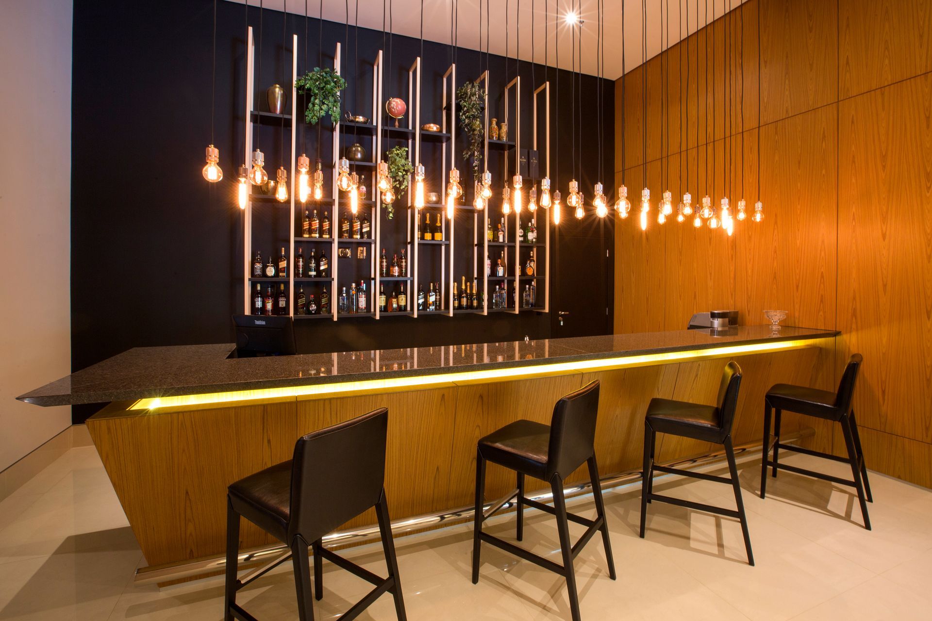 Um bar com um balcão longo e cadeiras em uma sala.