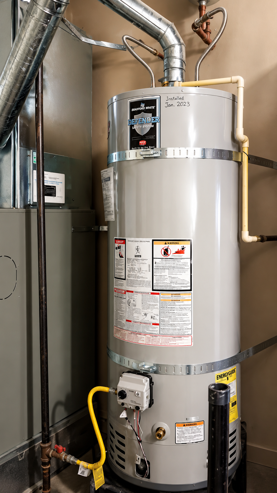 Tall gray water heater with pipes and labels in a utility closet Tall gray water heater with pipes and labels in a utility closet