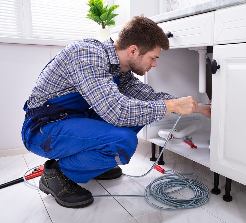 Plumber Cleaning Clogged Pipe — Monroe, WA — Hudy Plumbing & Heating Inc Plumber Cleaning Clogged Pipe — Monroe, WA — Hudy Plumbing & Heating Inc