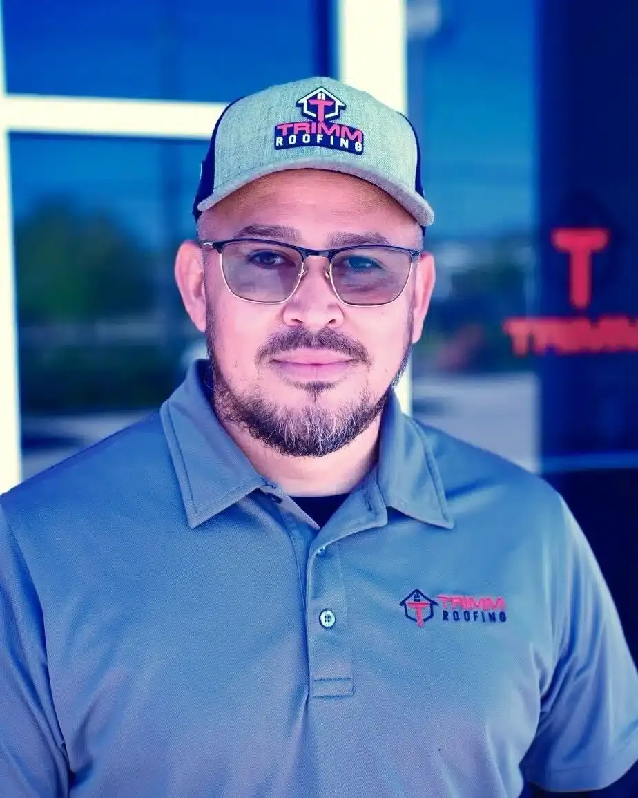A man wearing a hat and glasses is standing in front of a building.