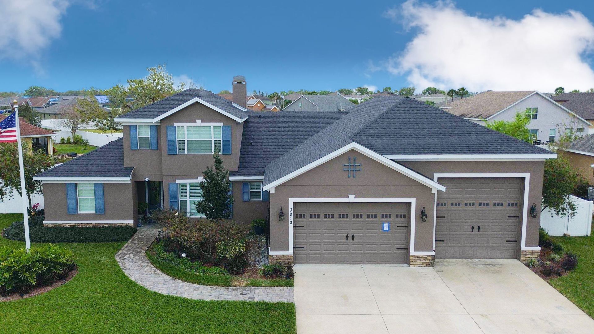 A large brick and stone house with a black roof and a chimney.