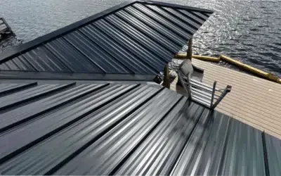 A black metal roof is sitting on top of a wooden deck next to a body of water.