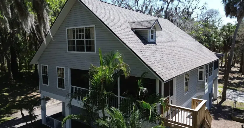 An aerial view of a large house with a screened in porch surrounded by trees.