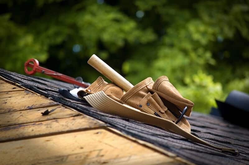 A tool belt is laying on top of a wooden roof.