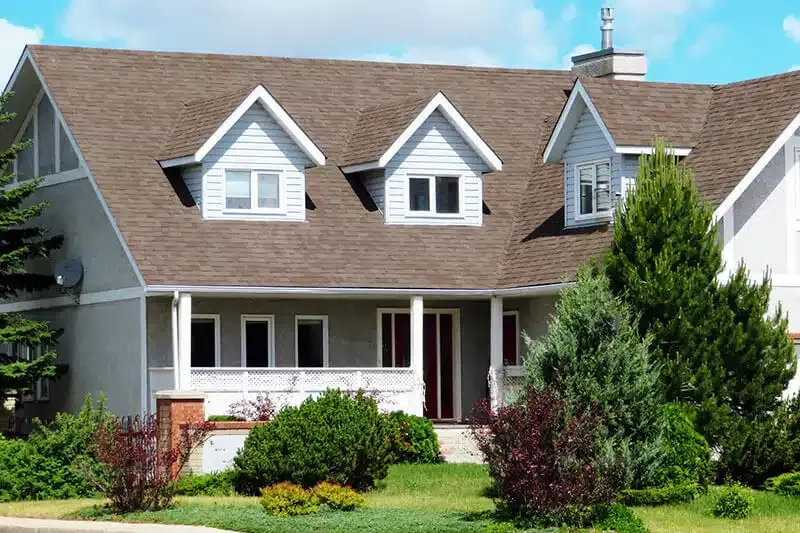 A large white house with a brown roof and a porch.