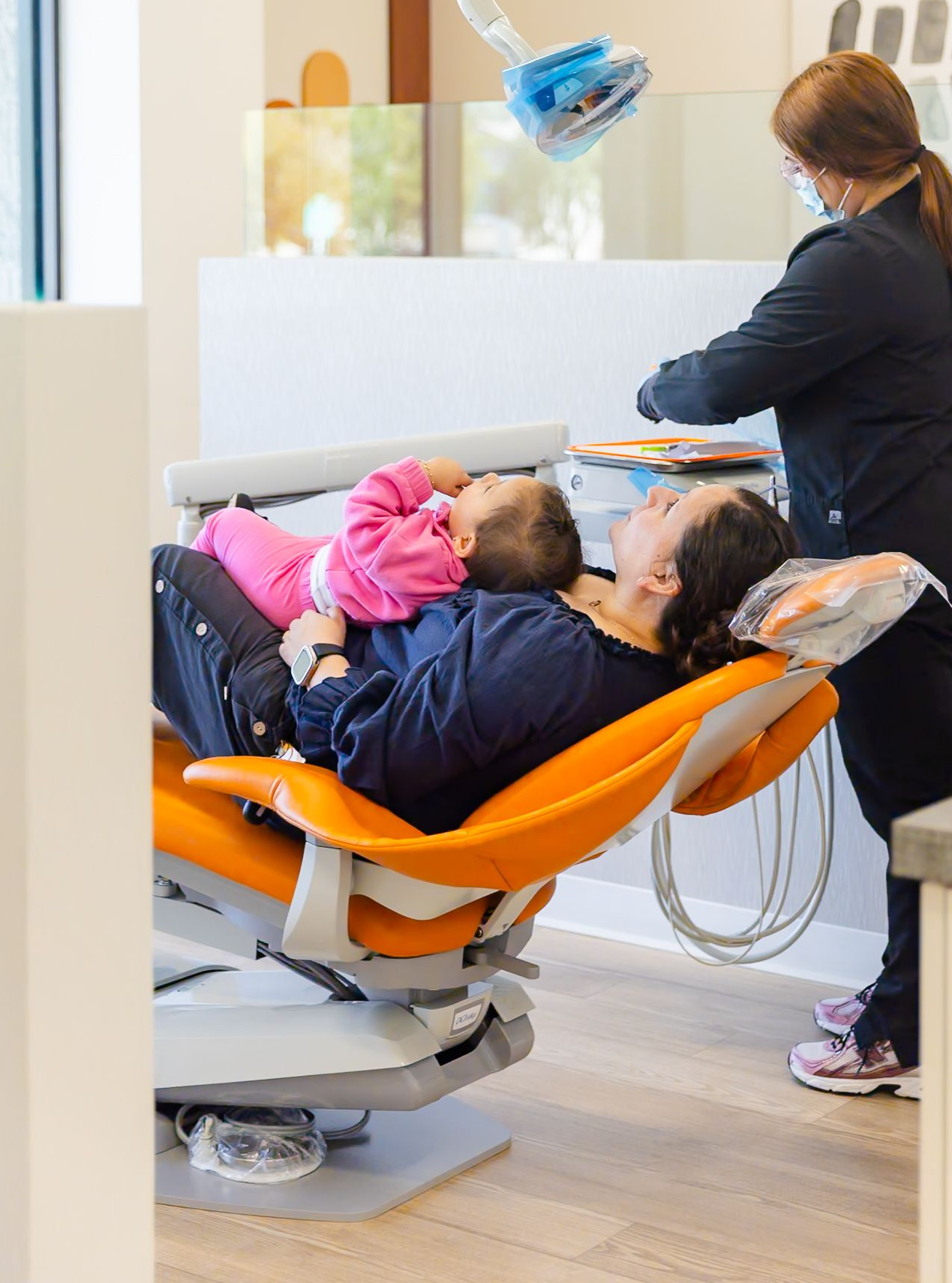 Smiling baby wearing a striped hat and onesie, lying on a white fluffy rug.