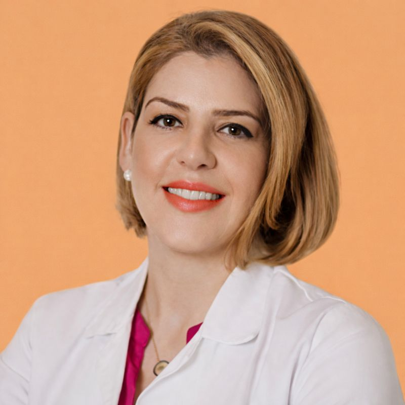Woman in a white lab coat with crossed arms, smiling.