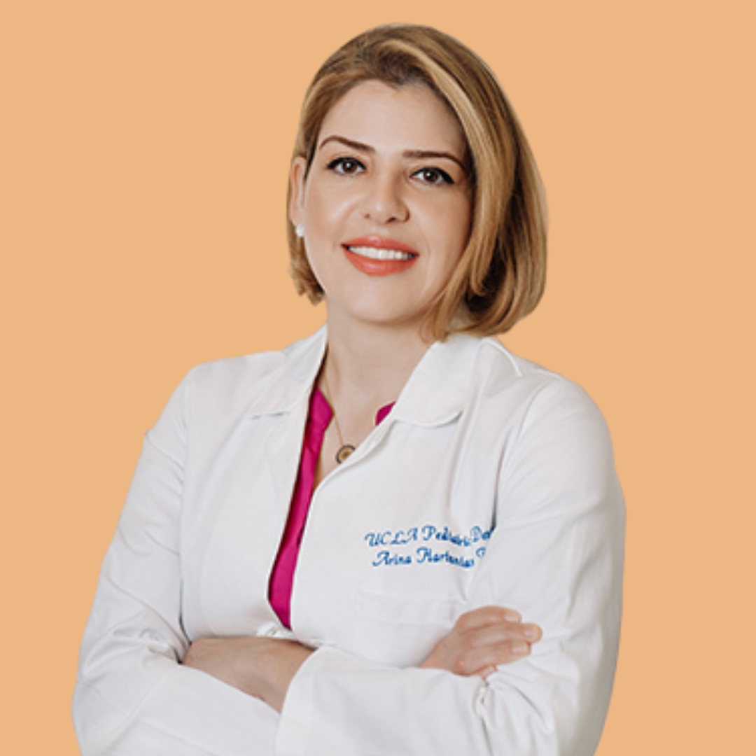 Woman in white coat, arms crossed, smiling. Text on coat: 