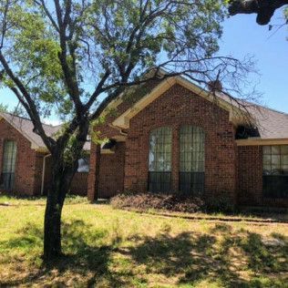 A brick house with a tree in front of it.