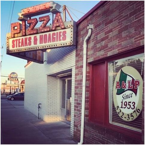 A brick building with a sign that says pizza steaks and hoagies