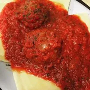 A close up of a plate of food with tomato sauce and meatballs