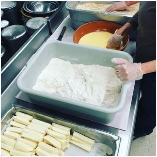 A person is preparing mozzarella sticks in a kitchen